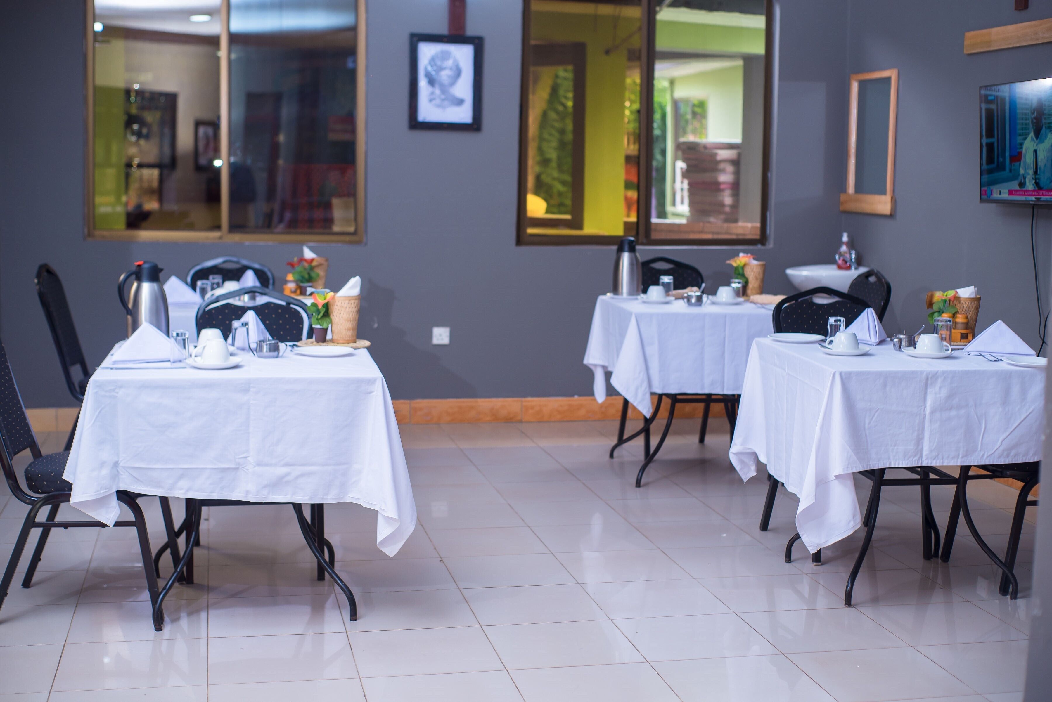 A dining area with tables set for service, chairs, and a coffee station.