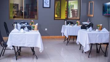 A dining area with tables set for service, chairs, and a coffee station.