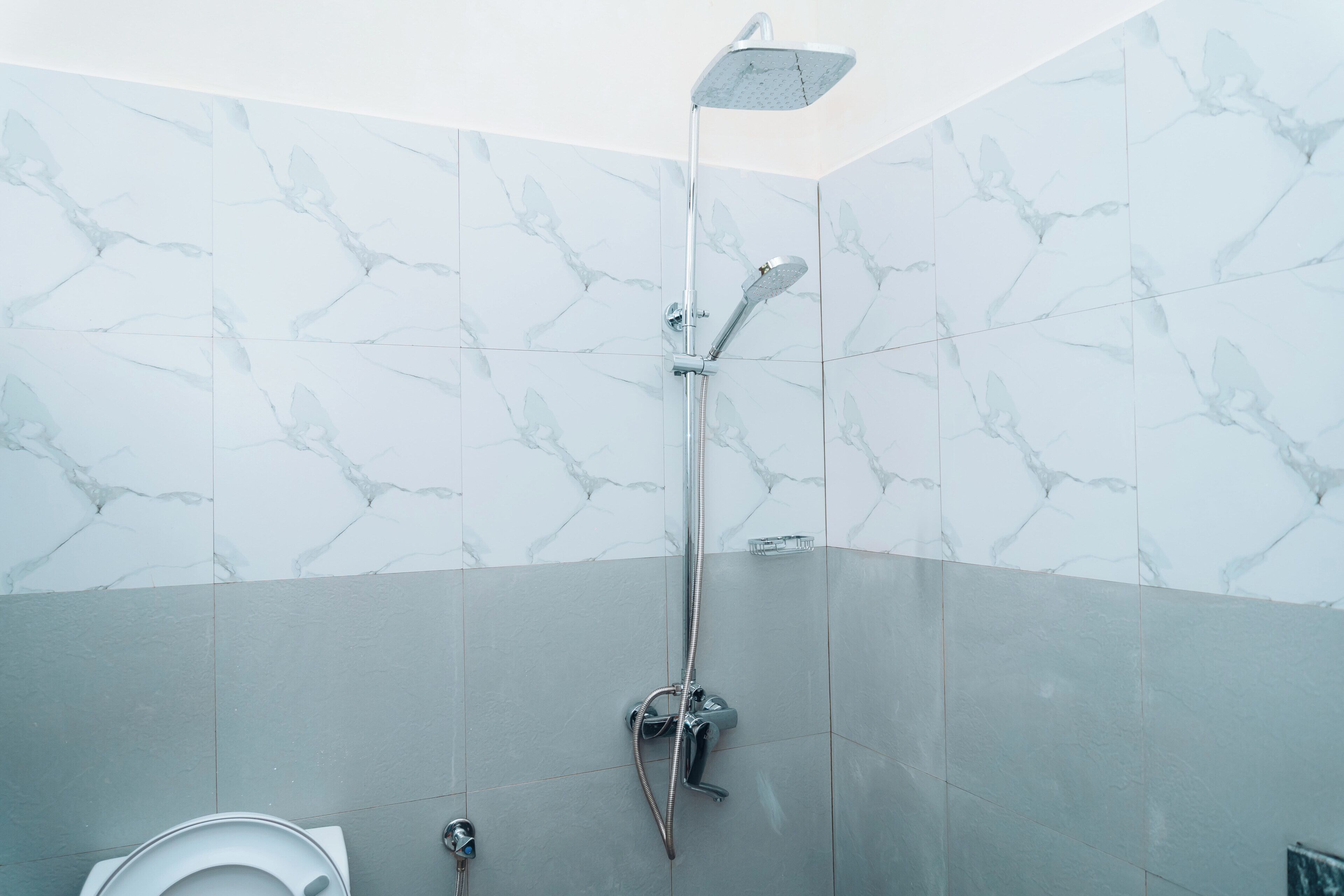Une salle de bain avec douche, toilettes et murs décorés d’un motif imitant le marbre.