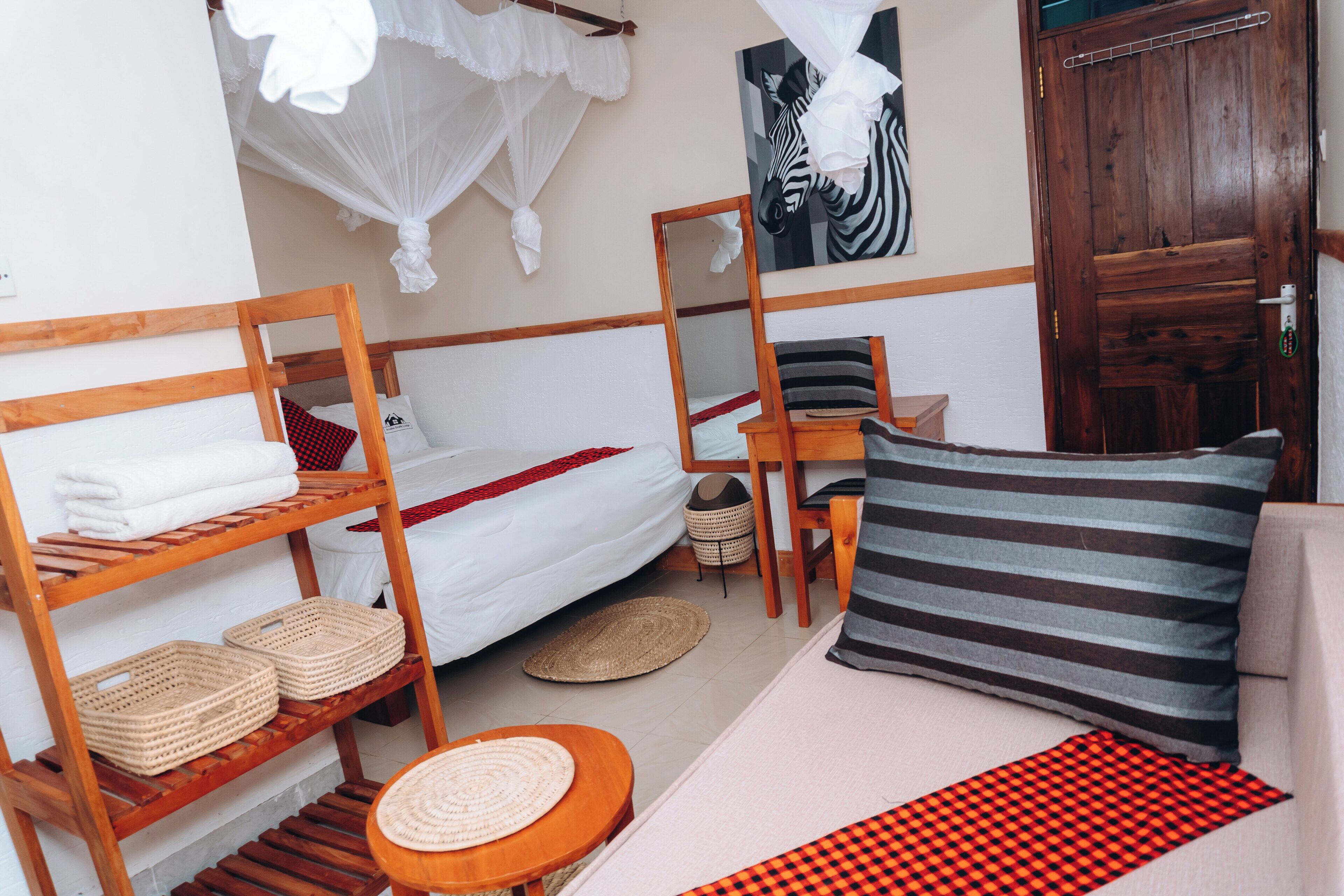 Una habitación con literas, una mesita, una silla, una cesta y una puerta.