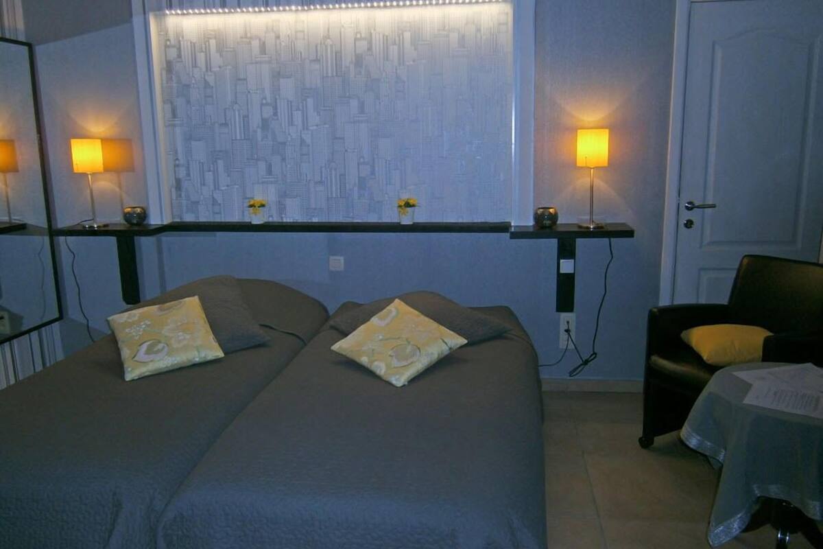 A hotel room with two beds, a chair, and a window with a cityscape view.
