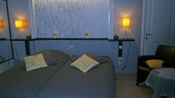 Een hotelkamer met twee bedden, een stoel en een raam met uitzicht op de stad.