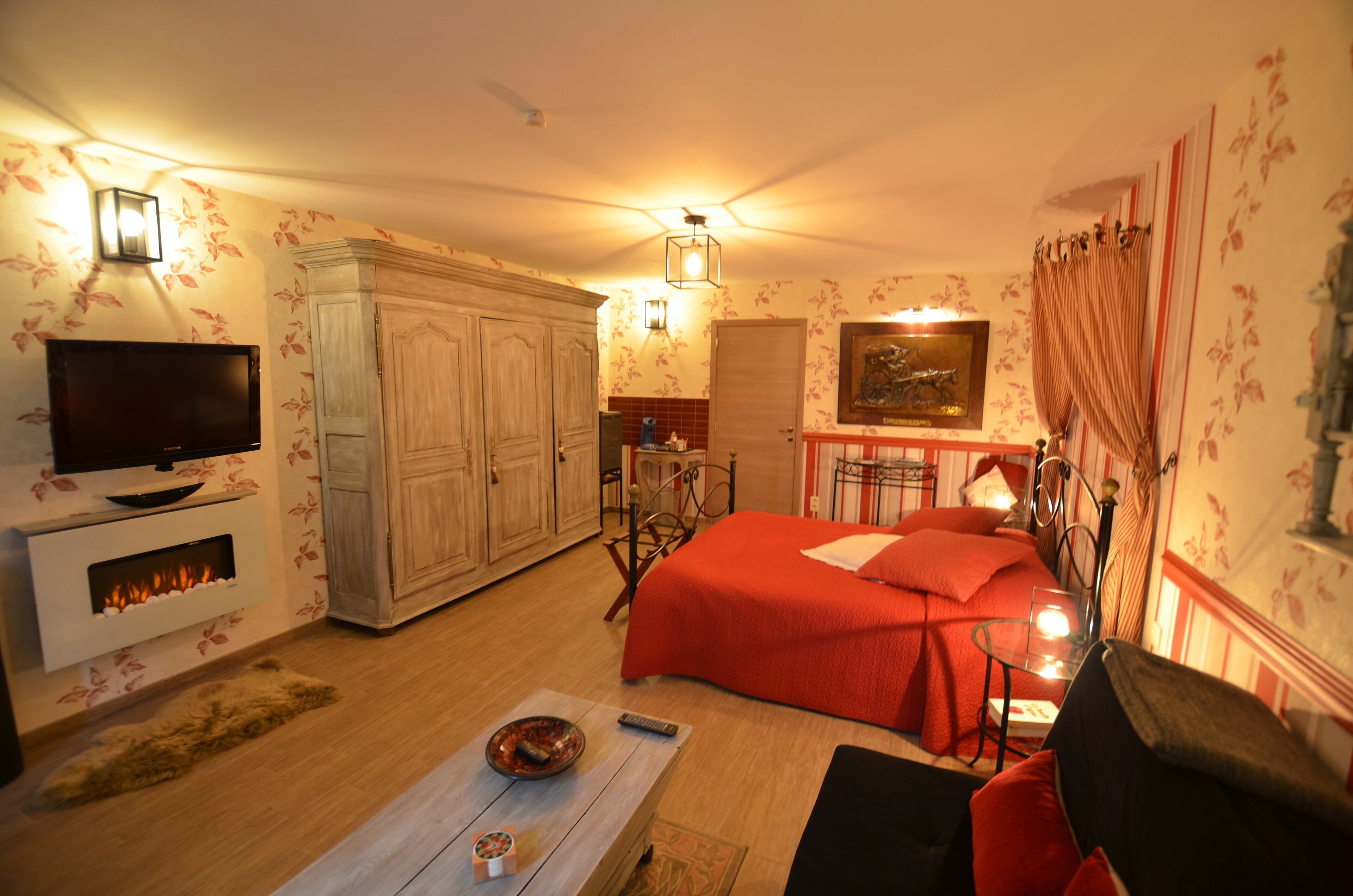 A cozy room with a bed, a television, a fireplace, and a dining area.