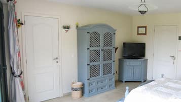 Une chambre à coucher avec un lit, une armoire, une télévision et une petite plante.