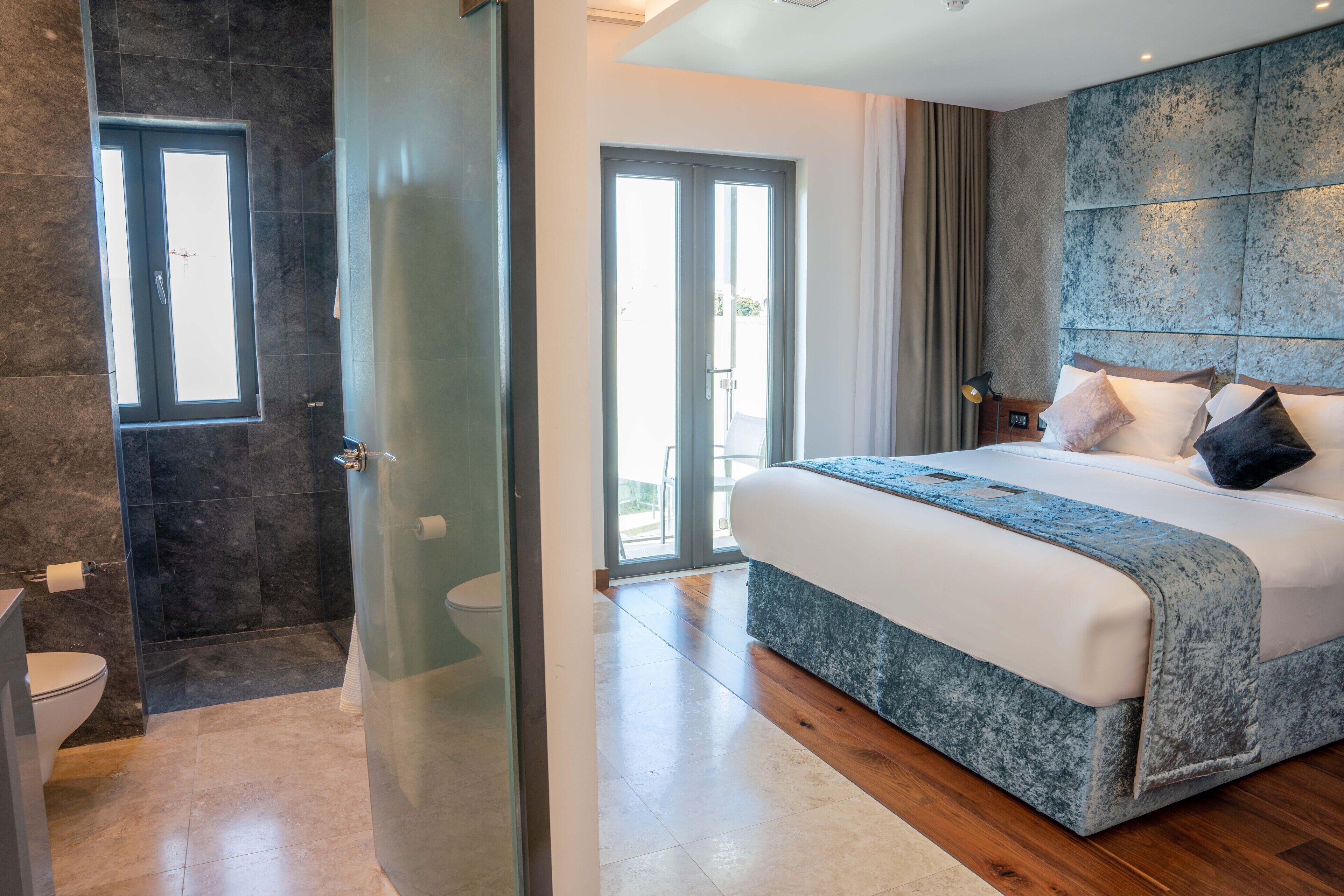 Un dormitorio moderno con una cama grande, cabina de ducha de vidrio y vistas al exterior.