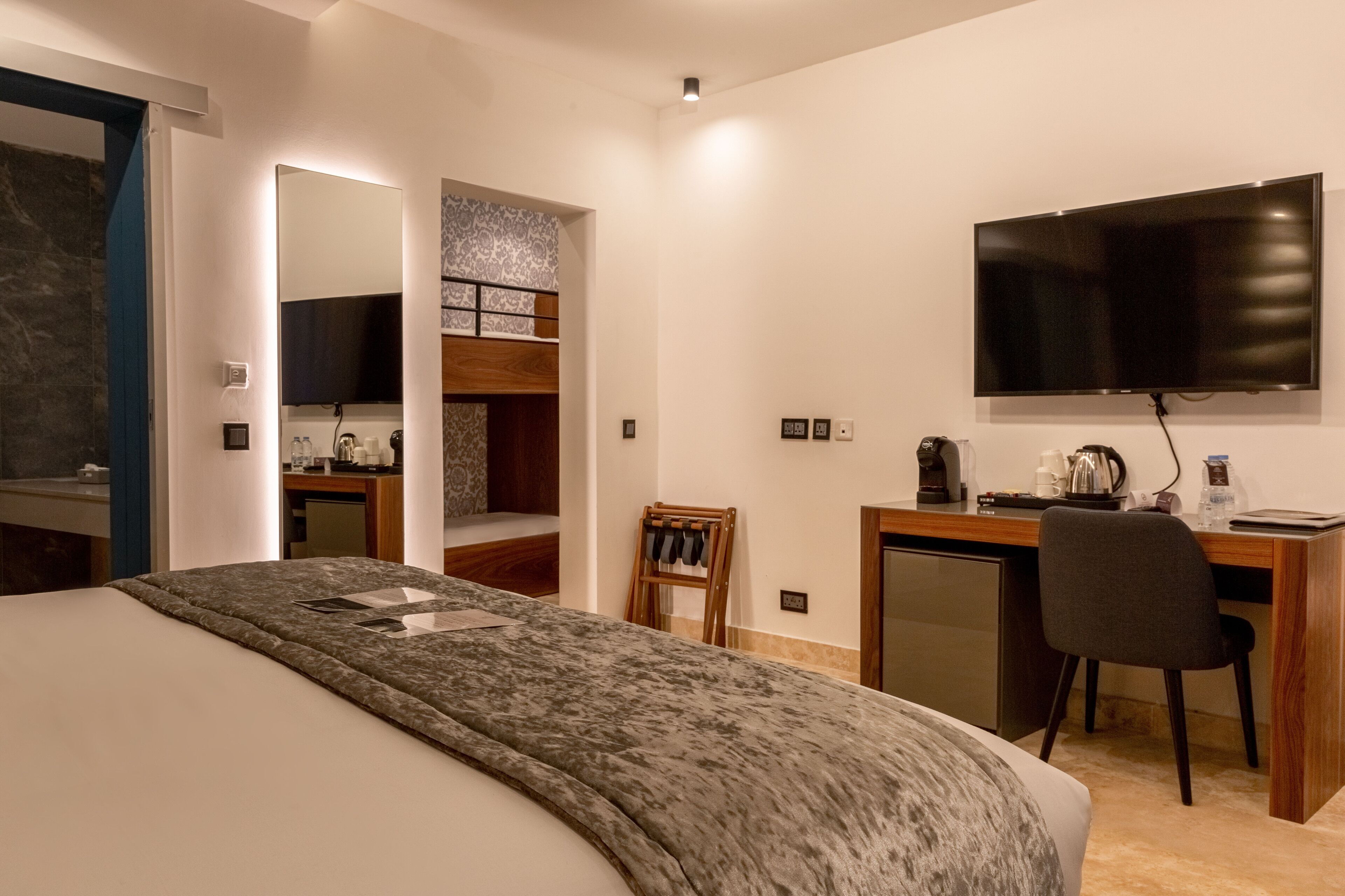 Una camera d'albergo moderna con un letto grande, una scrivania con una sedia, una TV a schermo piatto e un angolo cottura.