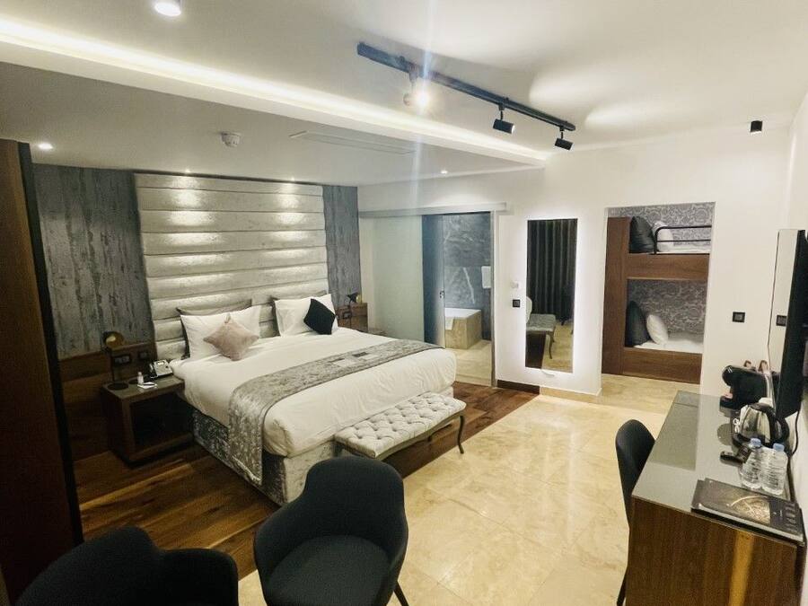 A modern hotel room with a large bed, a desk, and two chairs.