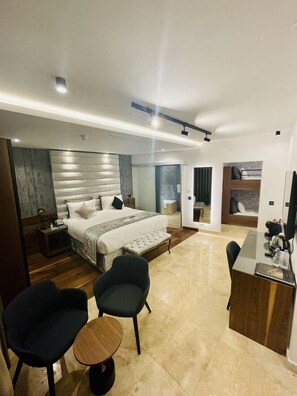 Une chambre d’hôtel moderne, dotée d’un grand lit, d’un bureau et de deux chaises.