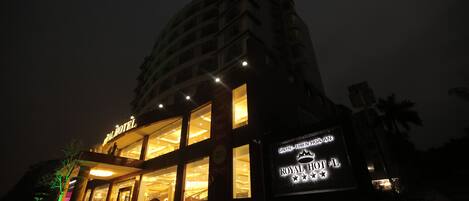 Un hotel con un letrero llamativo que dice "ROYAL HOTEL" y una entrada grande iluminada.