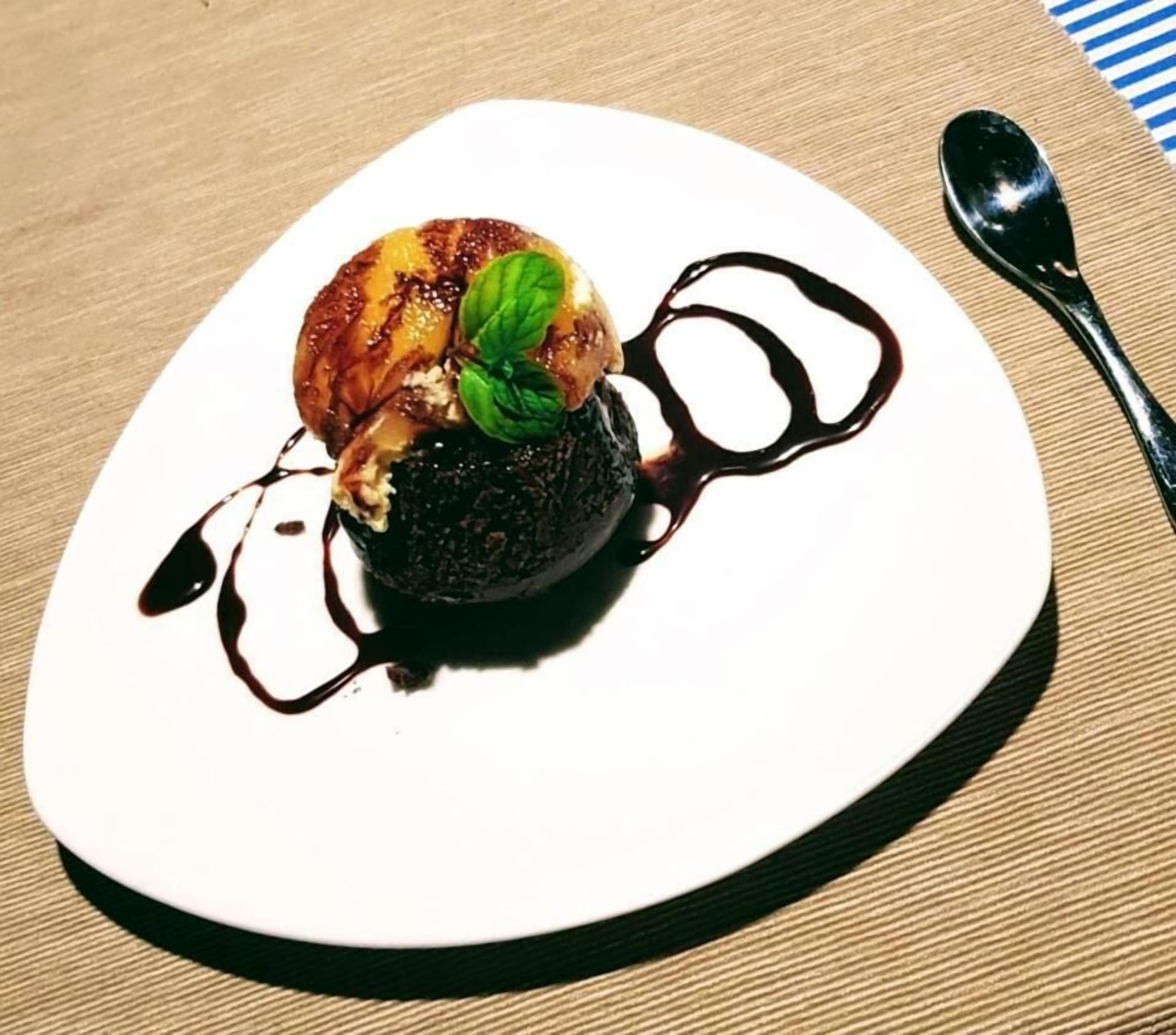 A dessert on a white plate with a spoon beside it.