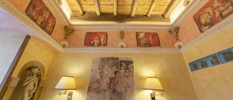 Una habitación con techo de madera, frescos y un mural grande.