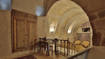 Un intérieur rustique avec une table à manger en bois, des chaises et un mur en pierre.