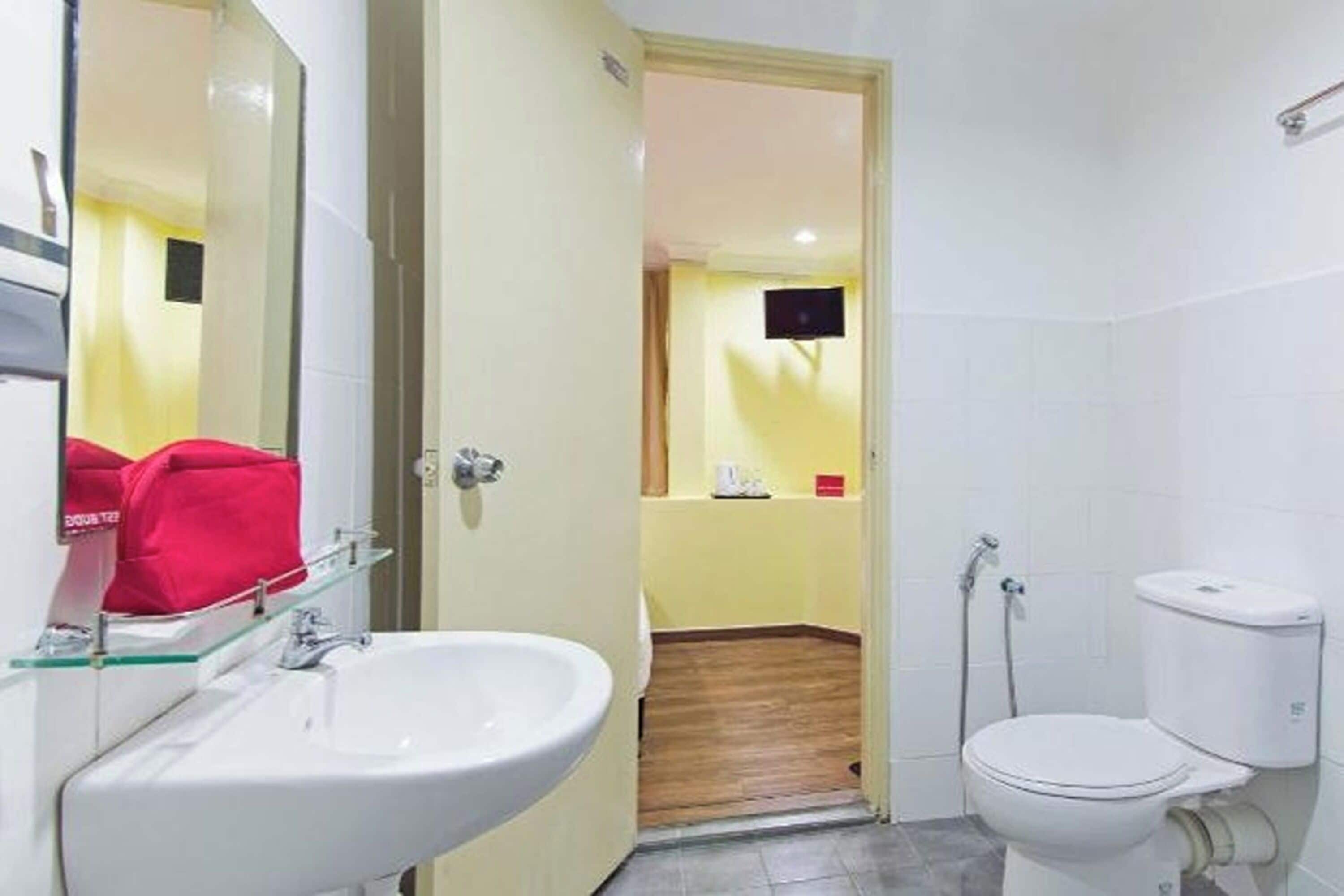 Une salle de bain avec un lavabo blanc, des toilettes et un miroir.