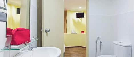 Une salle de bain avec un lavabo blanc, des toilettes et un miroir.