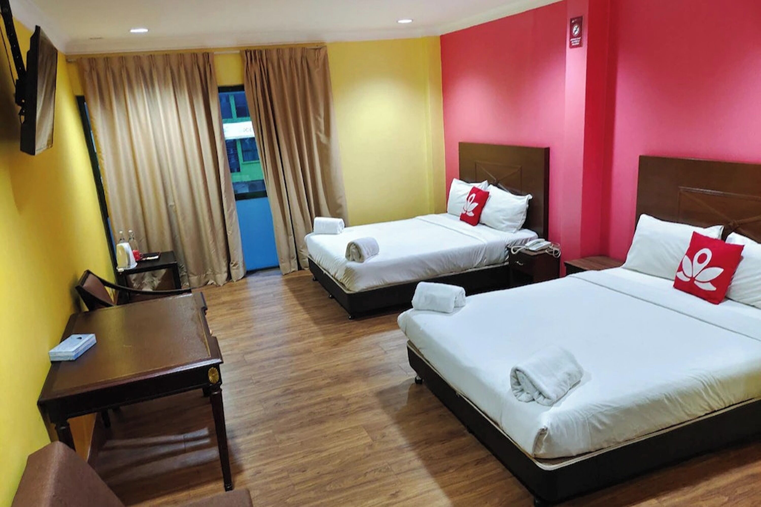 A hotel room with two beds, a desk, and a chair.