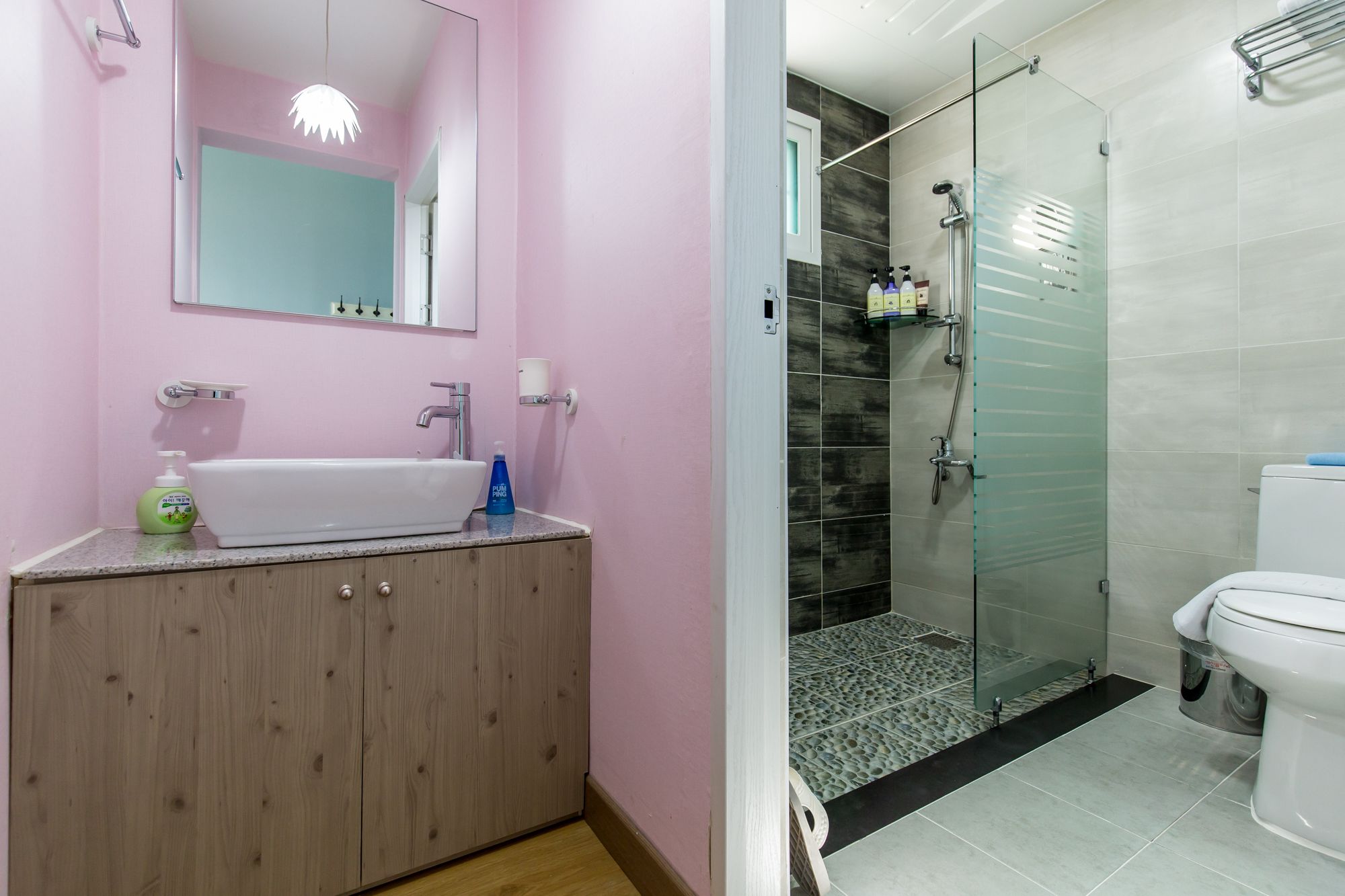 A bathroom with a wooden vanity, a white sink, and a glass shower enclosure.