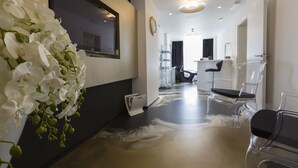A modern hotel lobby with a clear glass reception desk, a large mirror, and a white orchid arrangement. - B Gold Luxury Rooms (Split)