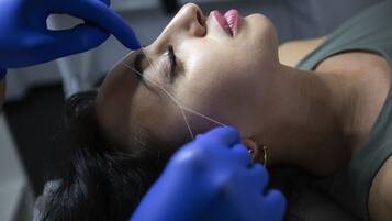 Une personne allongée, subissant un traitement médical au niveau du visage.