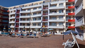 A hotel with multiple balconies, a pool area with sun loungers and umbrellas, and a wooden deck. - Central Plaza Apart Hotel (Sunny Beach)
