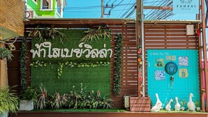 Facciata di un edificio con parete verde, scritte in thailandese e piante ornamentali.