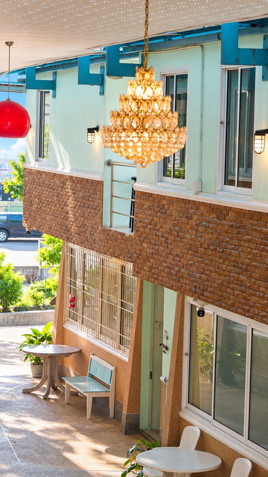 L’extérieur d’un hôtel avec une façade en briques, un balcon doté d’une rambarde en métal et un lustre suspendu.