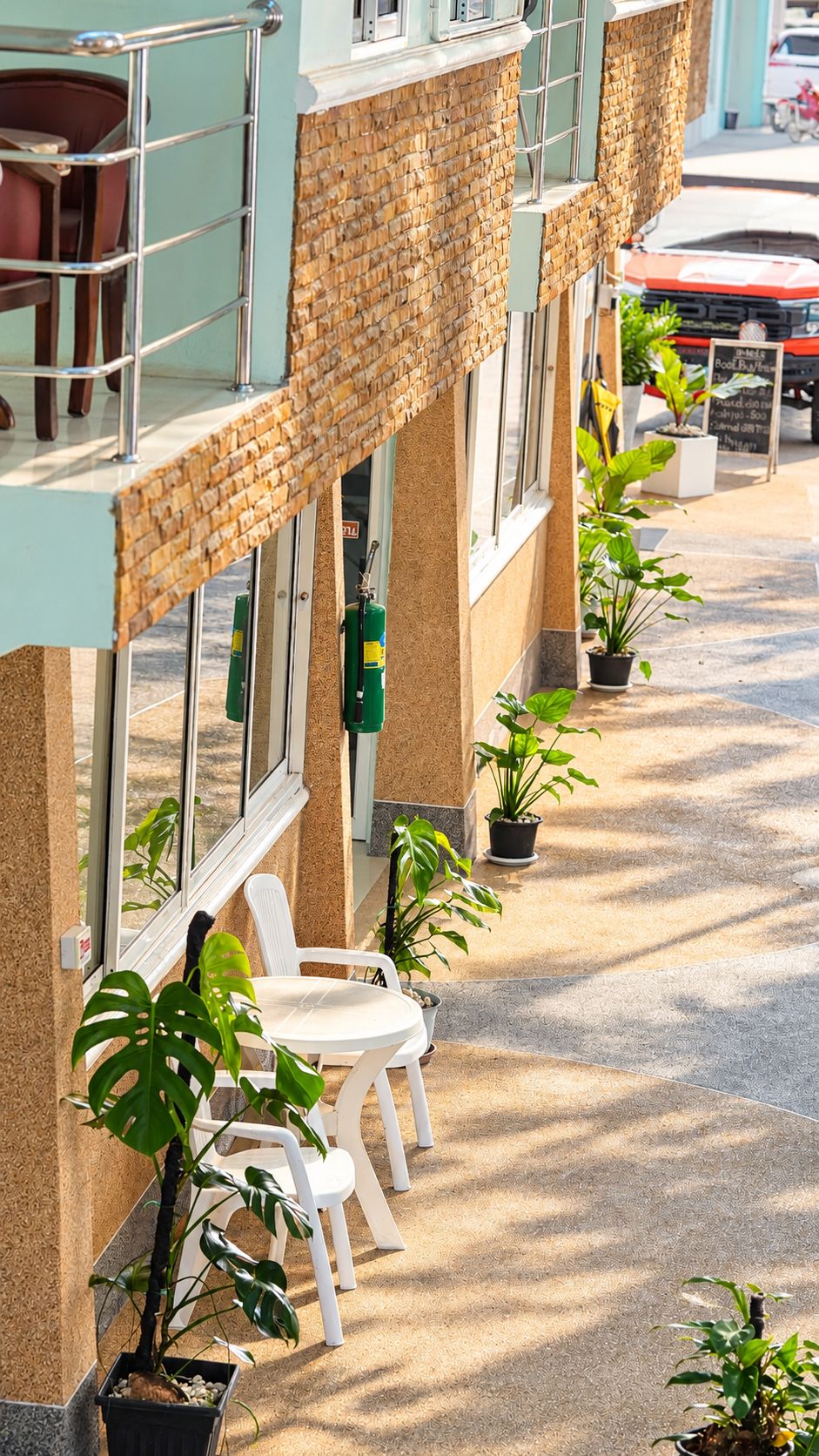 A hotel exterior with a brick facade, outdoor seating, and potted plants.