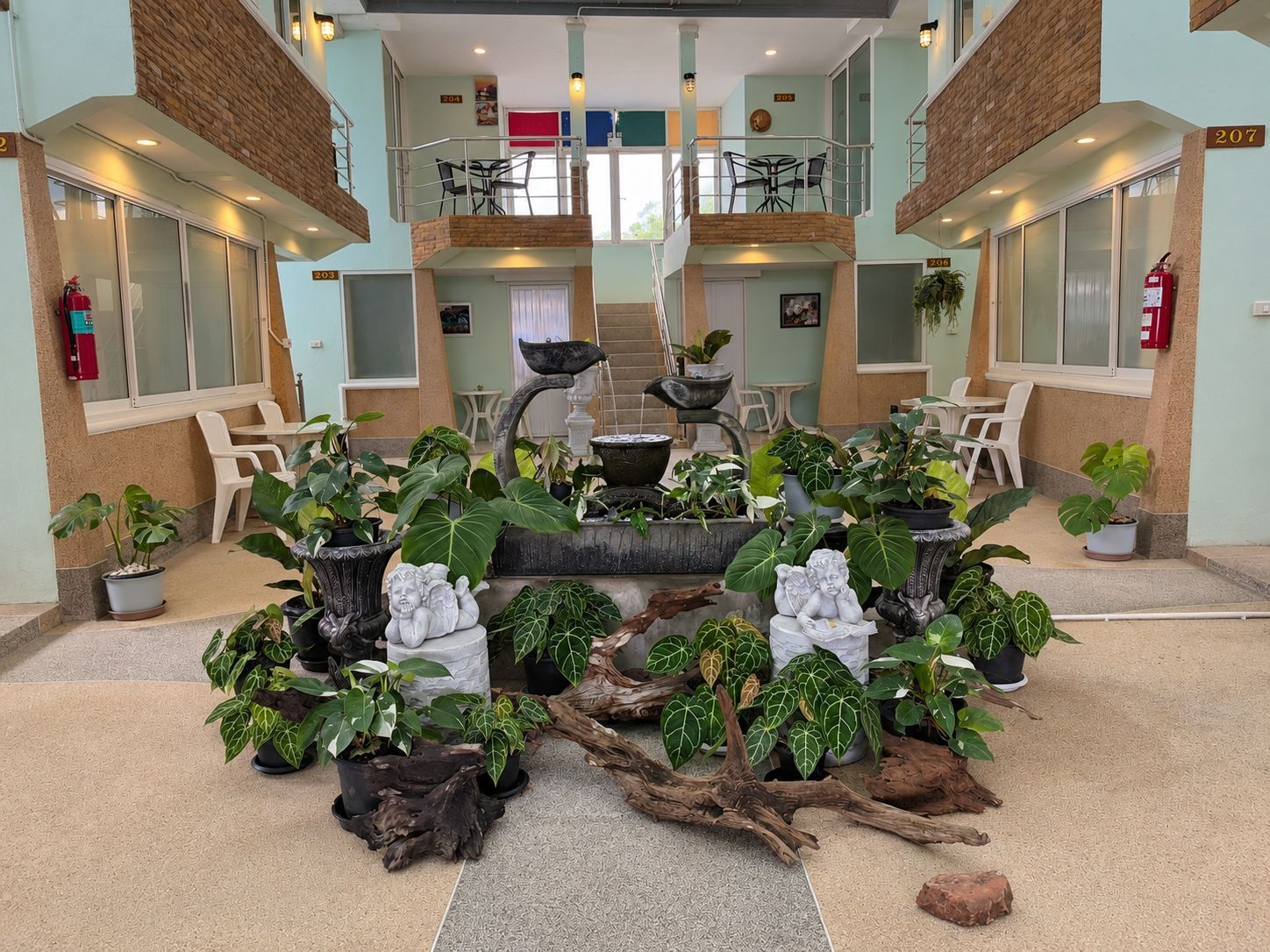 Un hall d’entrée doté d’une fontaine centrale, de plusieurs espaces aménagés pour s’asseoir et de plantes en pot.