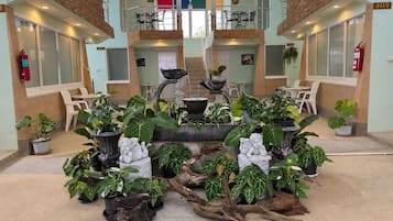 A lobby with a central fountain, multiple seating areas, and potted plants.