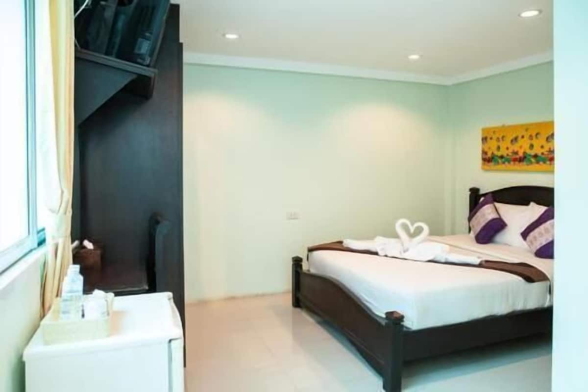 Un dormitorio con cama, mesita de noche, ventana y un cuadro en la pared.