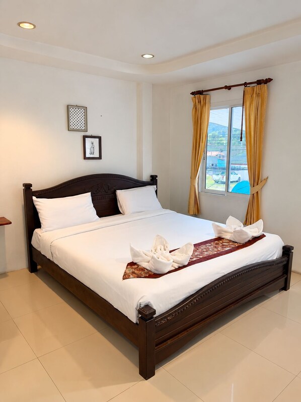 A neatly made bed with a white comforter and pillows, a wooden headboard, a window with curtains, and a small bedside table. - Fahsai Bay Villa (Krabi)