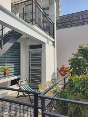 A balcony with a chair, a hanging plant, and a door with a metal gate. - Moon 2 (Tainan)