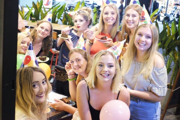 A group of people at a party with balloons and party hats. - Borough Capsule Hostel Bali (Legian)