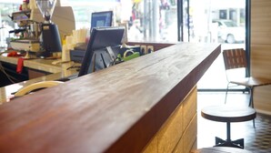 A wooden counter with a coffee machine and a computer monitor. - Borough Capsule Hostel Bali (Legian)