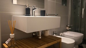 A modern bathroom with a white sink, a glass shower enclosure, and a wooden vanity. - 2Naples rooms (Naples)