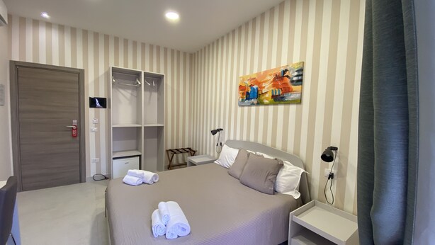 A hotel room with a bed, a wardrobe, a desk, and a painting on the wall. - 2Naples rooms (Naples)