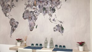 A dining area with a world map mural on the wall, a table with chairs, and two potted plants. - 2Naples rooms (Naples)