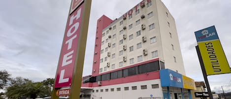 A hotel with multiple floors, a prominent entrance, and a parking area with cars.