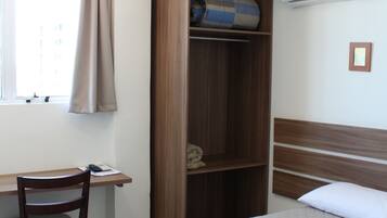 Een slaapkamer met een bed, een bureau, een stoel, een kledingkast en een airconditioning.