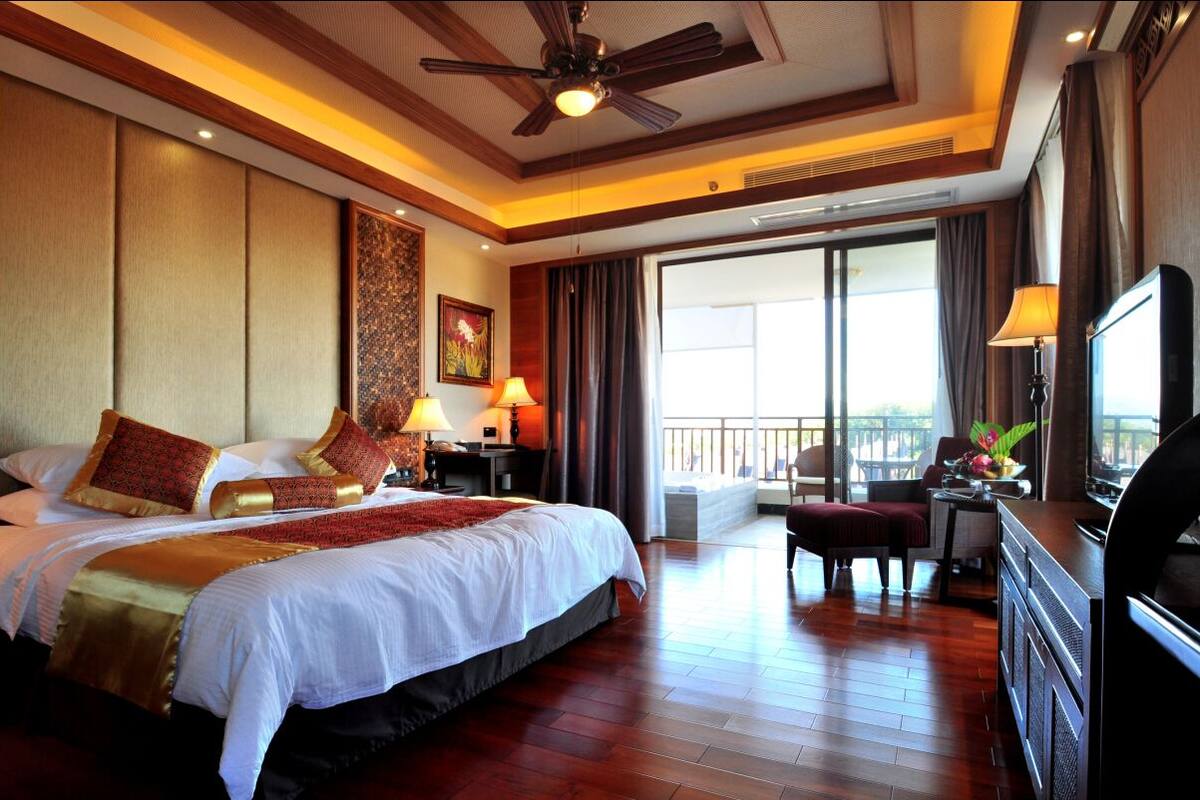 Una habitación de hotel con una cama grande, un escritorio, un televisor y un balcón con vistas.
