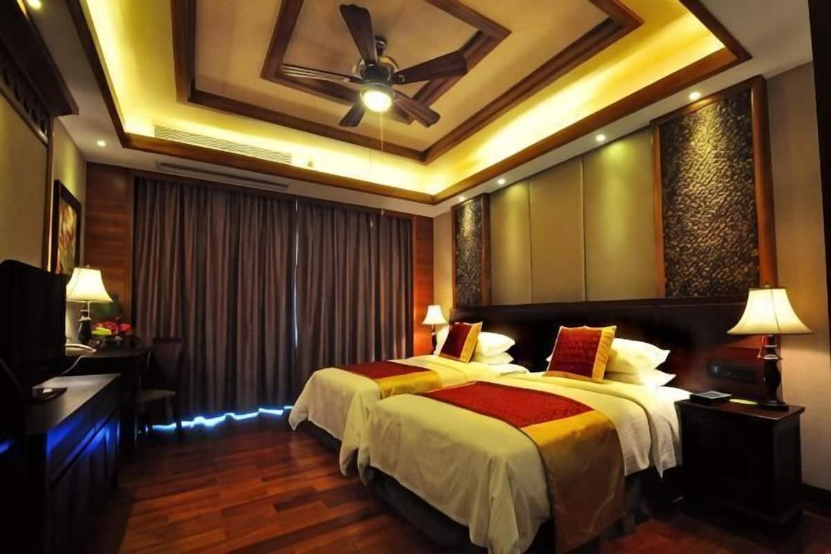 Une chambre dâhĂŽtel avec deux lits, un ventilateur de plafond, un bureau avec une lampe et une tĂ©lĂ©vision.