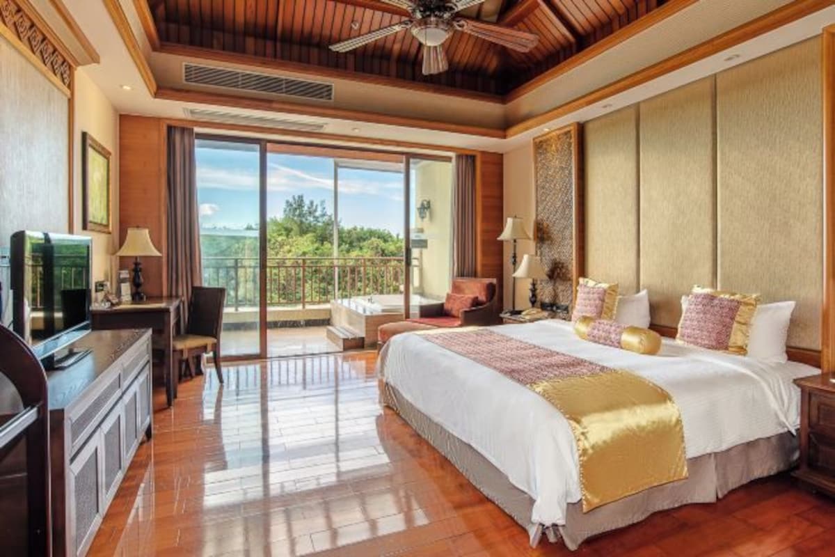 Un dormitorio amplio con una cama grande, un escritorio y una silla. Cuenta con un balcón con vistas al exterior.