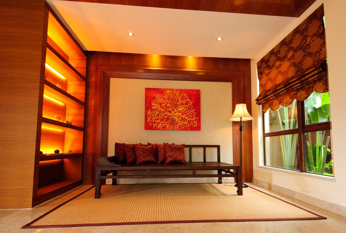 A room with a wooden bench, a red abstract painting, a lamp, and a window with a view of greenery.