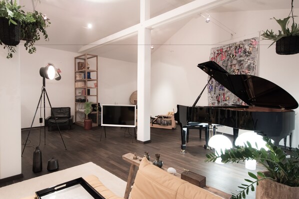 Un salon spacieux avec un grand piano, une bibliothèque et un tableau de grande taille.