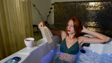 A woman in a bathtub with a cup of coffee and a book.