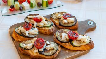 Una tabla de madera con tostadas cubiertas de verduras a la parrilla.