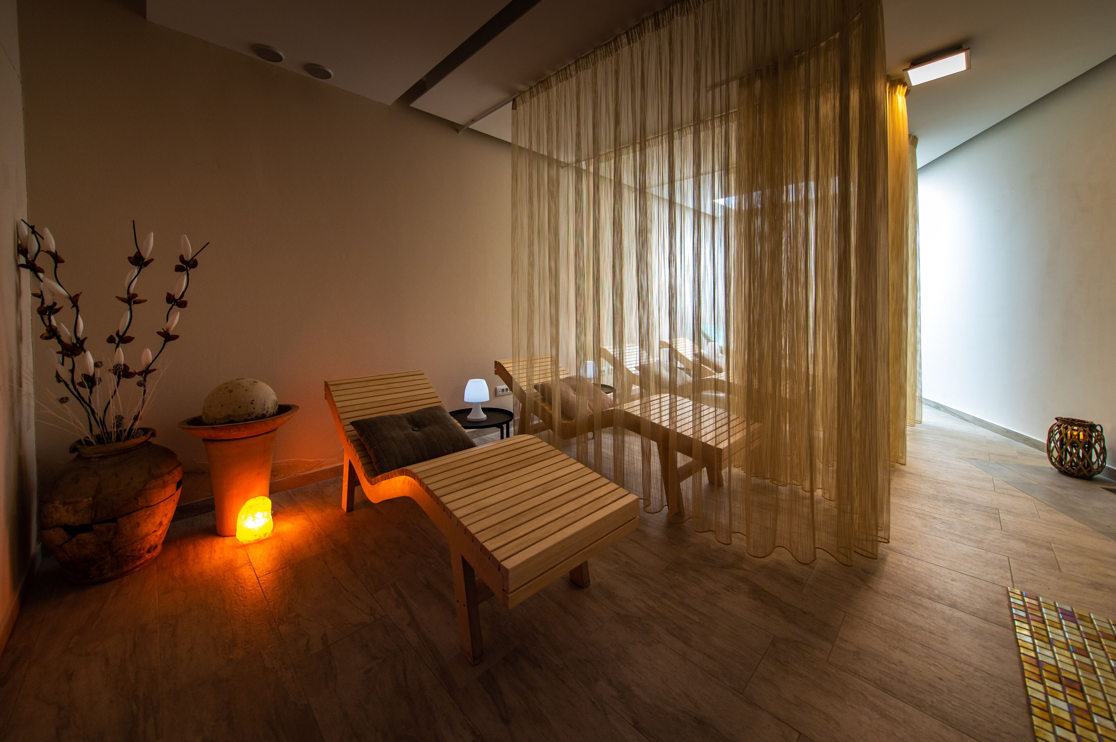 A modern room with a wooden bench, a small table, a potted plant, and a lamp.
