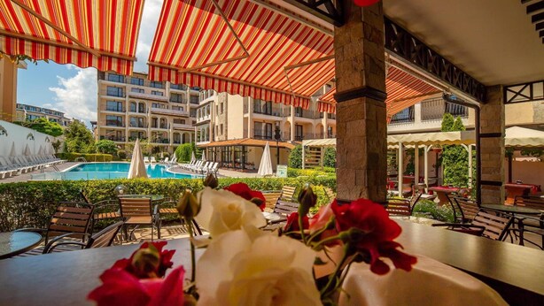 Zona de piscina hotelera con canopies a rayas, asientos al aire libre y vistas a la piscina.