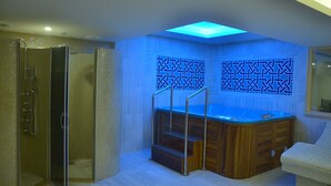 A modern bathroom with a glass-enclosed shower, a wooden bathtub, and a blue-lit wall. - Adranos Hotel (Bursa)
