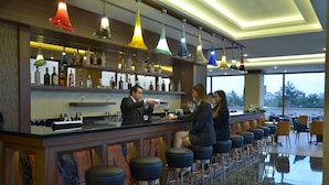 A bar area with a bartender, multiple stools, and a variety of bottles on shelves. - Adranos Hotel (Bursa)