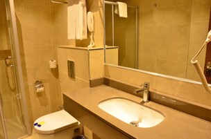 Un baño con lavamanos, espejo e inodoro.